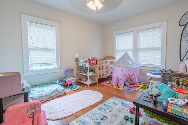 bedroom featuring ceiling fan, hardwood / wood-style floors, and multiple windows