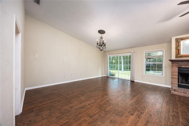 unfurnished living room with lofted ceiling, dark wood-type flooring, ceiling fan with notable chandelier, and a fireplace