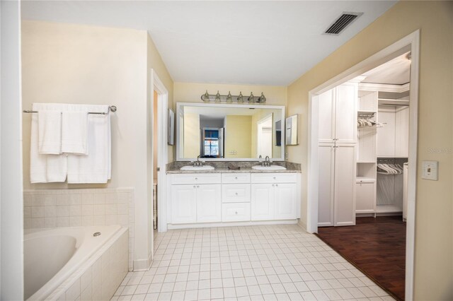 bathroom with vanity, a relaxing tiled tub, and hardwood / wood-style floors