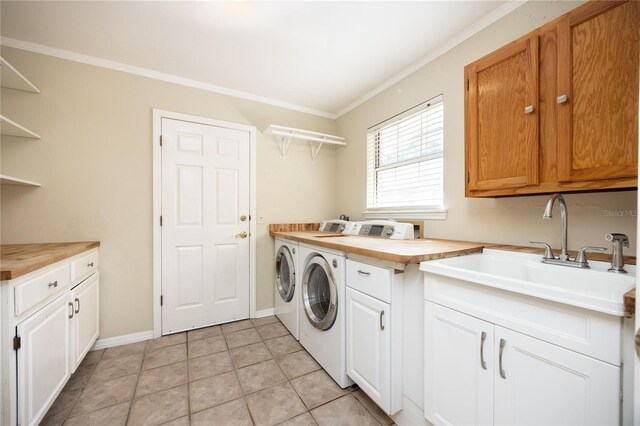 washroom featuring crown molding, independent washer and dryer, sink, light tile patterned flooring, and cabinets