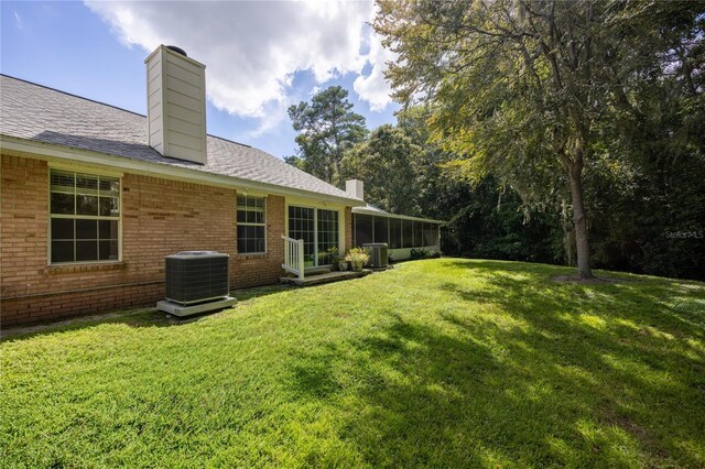 view of yard featuring a sunroom and central AC unit