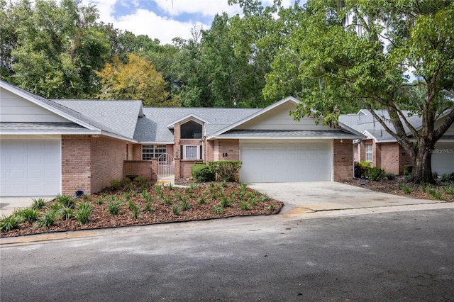 ranch-style home featuring an attached garage, roof with shingles, concrete driveway, and brick siding