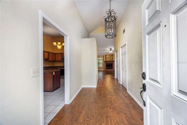 hall with a notable chandelier, high vaulted ceiling, and light hardwood / wood-style floors