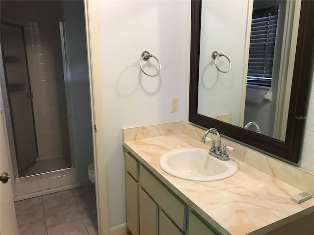 bathroom with vanity, a tile shower, tile patterned floors, and toilet