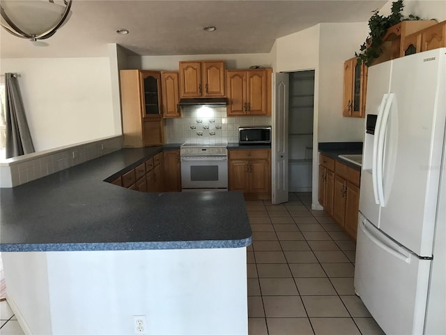 kitchen with white appliances, tile patterned floors, kitchen peninsula, and decorative backsplash