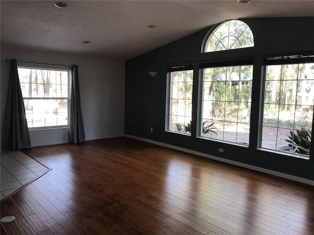 unfurnished room featuring lofted ceiling and dark hardwood / wood-style flooring