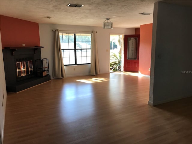 unfurnished living room featuring hardwood / wood-style flooring and a textured ceiling