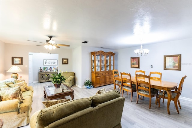 living area with light wood-type flooring, visible vents, baseboards, and ceiling fan with notable chandelier