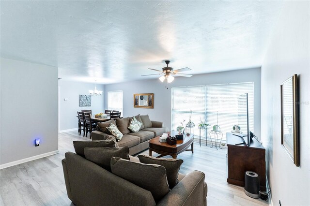 living area featuring light wood-style floors, plenty of natural light, baseboards, and a textured ceiling