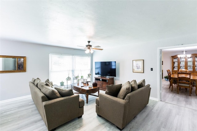 living area featuring light wood-style floors, baseboards, and ceiling fan with notable chandelier