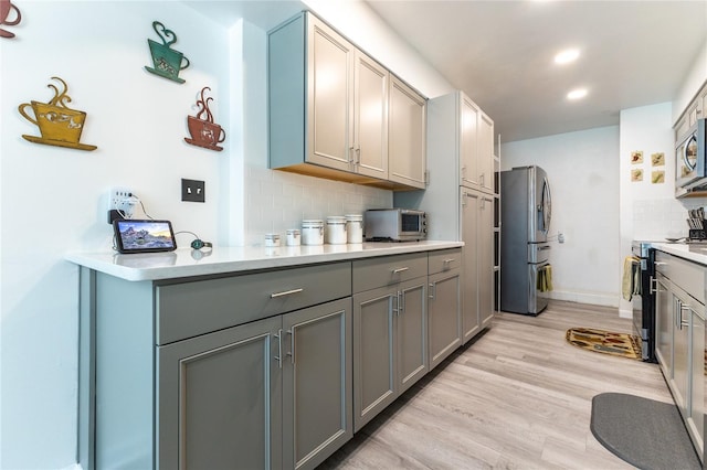 kitchen featuring range with electric cooktop, light countertops, light wood-type flooring, gray cabinets, and freestanding refrigerator