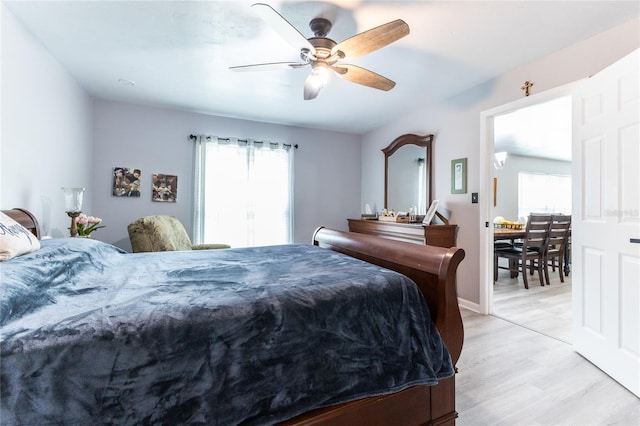 bedroom featuring light wood-type flooring, ceiling fan, multiple windows, and baseboards