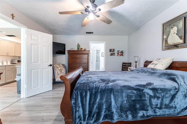 bedroom featuring light wood-type flooring, ceiling fan, lofted ceiling, and ensuite bathroom