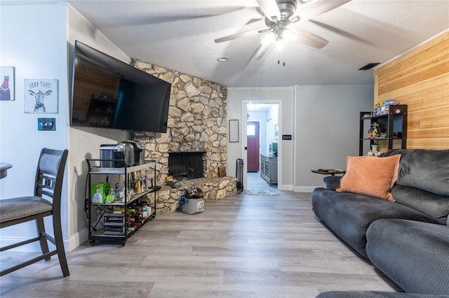 living area with a ceiling fan, a fireplace, visible vents, and light wood-style floors