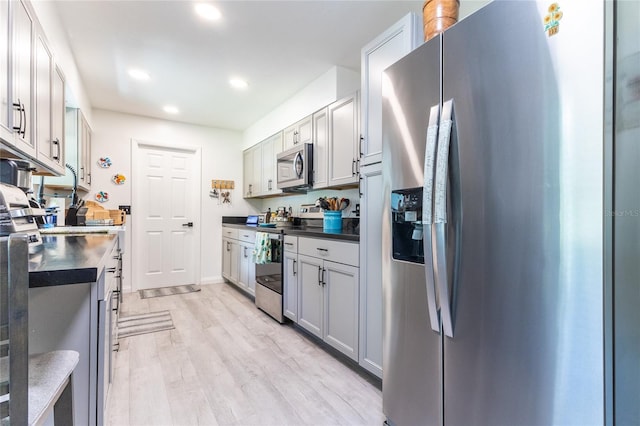 kitchen with stainless steel appliances, dark countertops, light wood finished floors, and recessed lighting