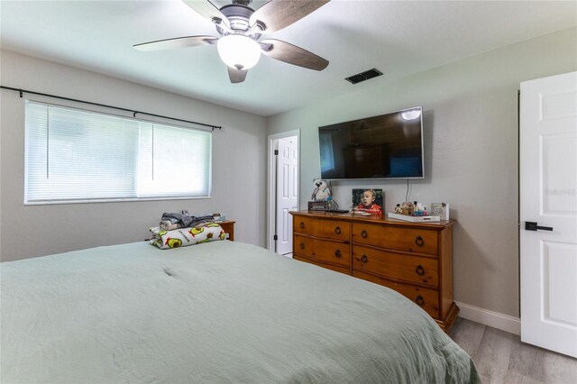 bedroom featuring light wood-style flooring, a ceiling fan, visible vents, and baseboards