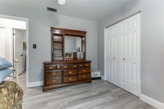 bedroom with light wood-style floors, baseboards, visible vents, and a closet