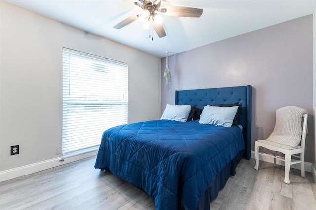 bedroom with light wood finished floors, a ceiling fan, and baseboards