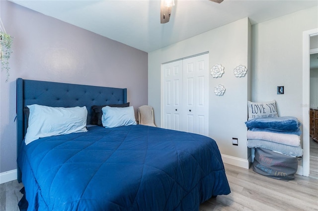 bedroom featuring light wood finished floors, ceiling fan, baseboards, and a closet