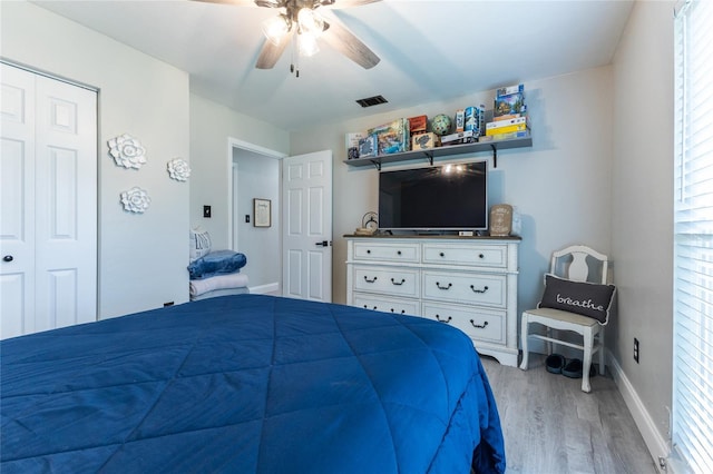 bedroom featuring baseboards, visible vents, a ceiling fan, light wood-type flooring, and a closet