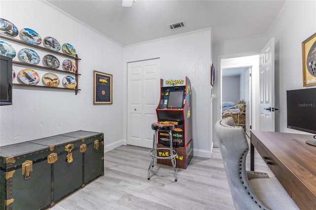 office space with baseboards, visible vents, crown molding, and light wood finished floors