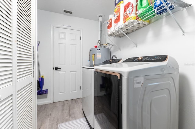 laundry area featuring laundry area, visible vents, light wood-style flooring, electric water heater, and washing machine and dryer