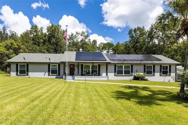 single story home featuring solar panels and a front yard