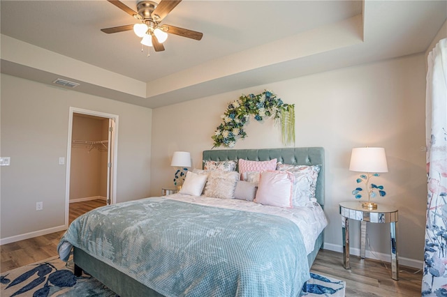 bedroom with visible vents, a tray ceiling, and wood finished floors