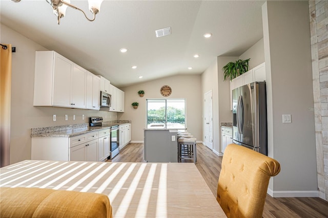 kitchen featuring appliances with stainless steel finishes, white cabinets, vaulted ceiling, and visible vents