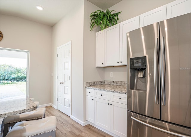 kitchen with light wood finished floors, light stone counters, white cabinetry, and stainless steel fridge with ice dispenser