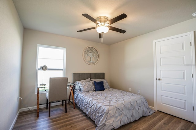 bedroom featuring a ceiling fan, dark wood-style flooring, and baseboards