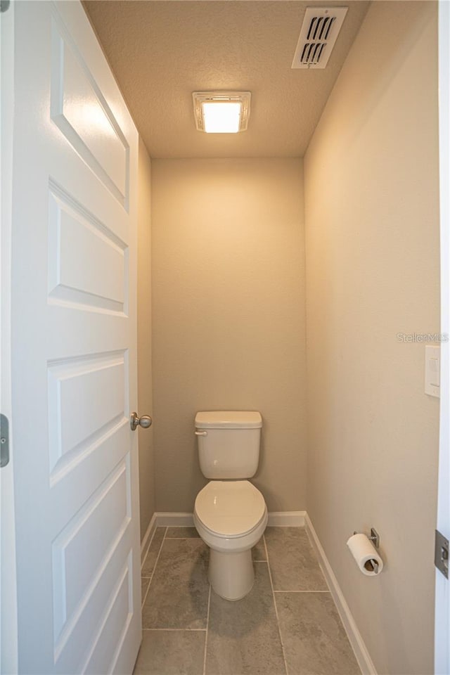 bathroom with toilet, tile patterned flooring, visible vents, and baseboards