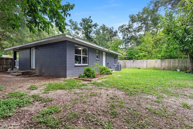 rear view of property featuring a lawn and central AC