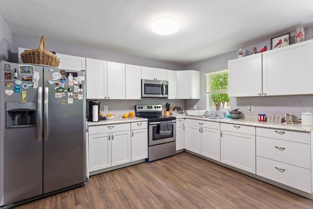 kitchen with wood-type flooring, sink, appliances with stainless steel finishes, and white cabinetry