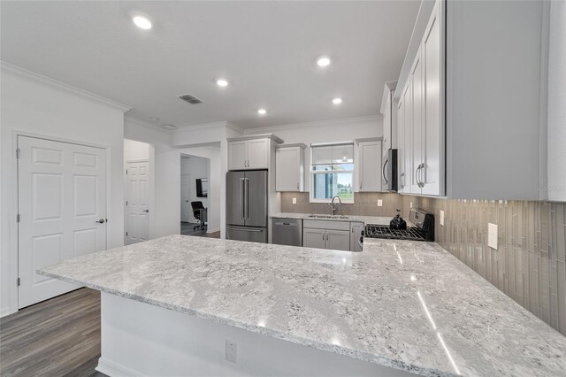 kitchen featuring ornamental molding, stainless steel appliances, kitchen peninsula, and sink