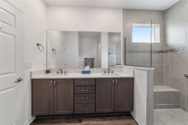 bathroom with wood-type flooring, tiled shower, and vanity