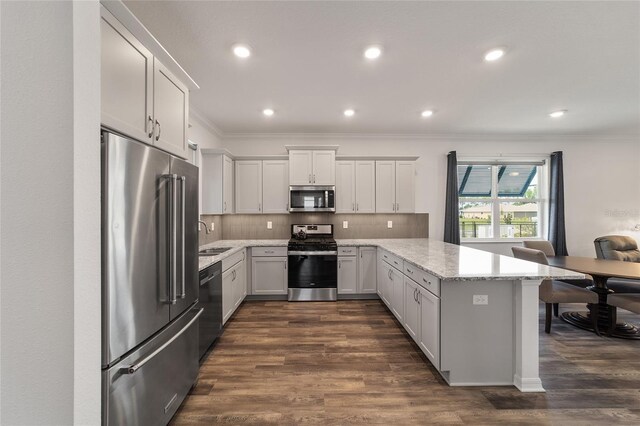 kitchen featuring light stone countertops, appliances with stainless steel finishes, dark wood-type flooring, and crown molding