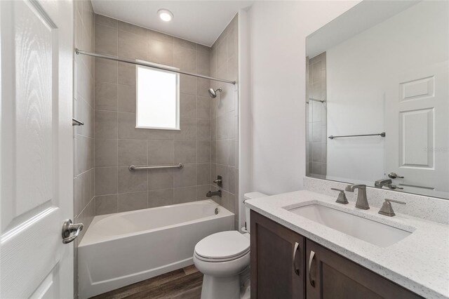 full bathroom with wood-type flooring, vanity, toilet, and tiled shower / bath combo