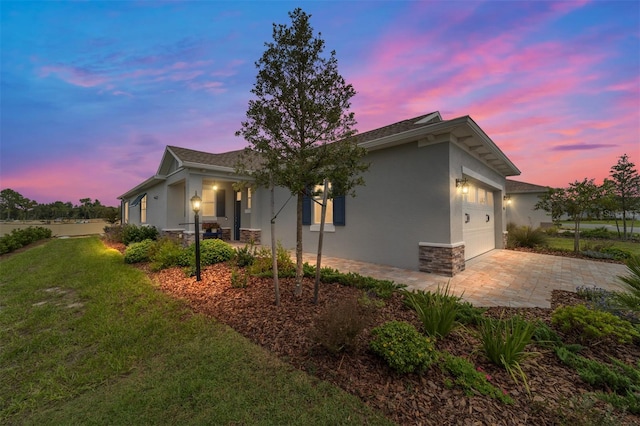 property exterior at dusk featuring a garage and a yard