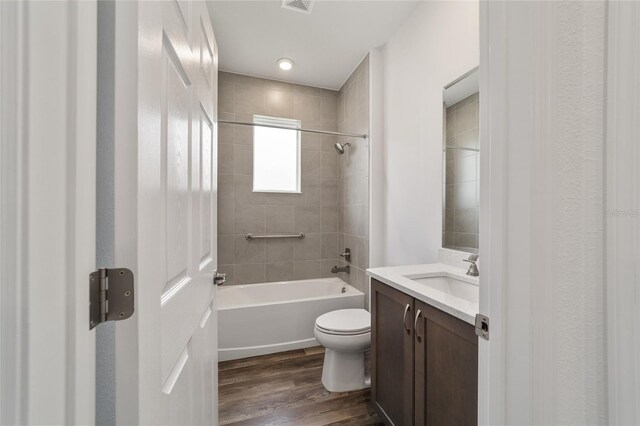 full bathroom featuring tiled shower / bath, hardwood / wood-style flooring, vanity, and toilet