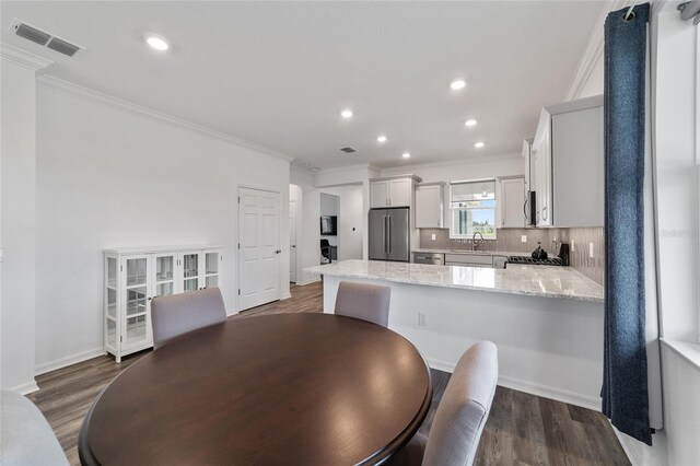 dining room with sink, dark hardwood / wood-style floors, and ornamental molding