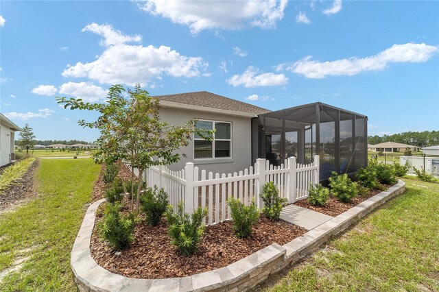 back of property with glass enclosure and a yard