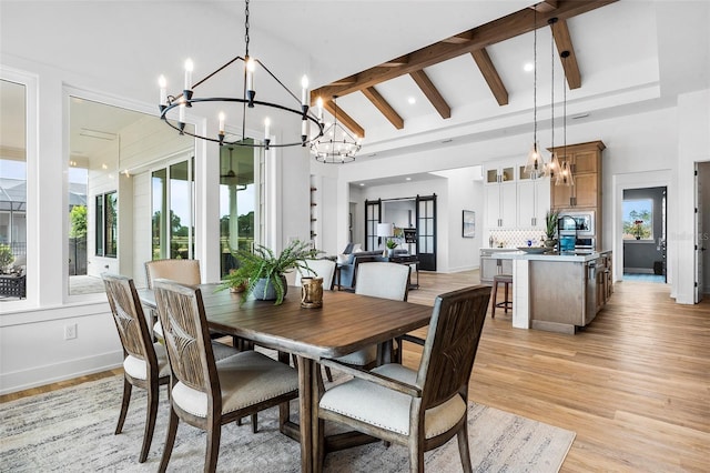 dining room featuring light wood-type flooring, vaulted ceiling with beams, and a barn door