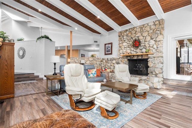 living room with beamed ceiling, high vaulted ceiling, hardwood / wood-style floors, a stone fireplace, and wooden ceiling