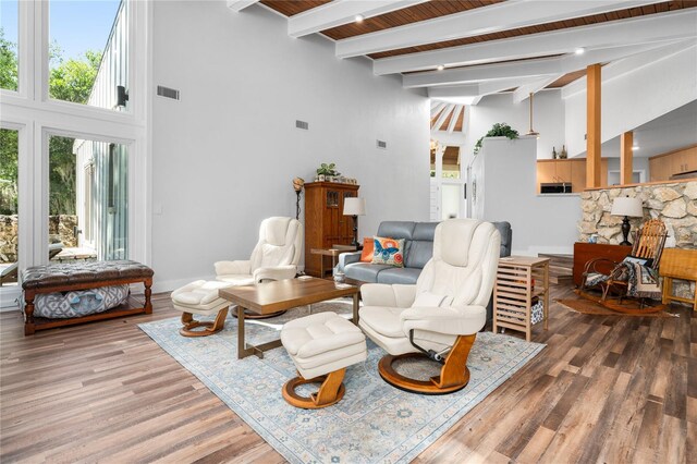 living room with a towering ceiling, beamed ceiling, and dark hardwood / wood-style floors