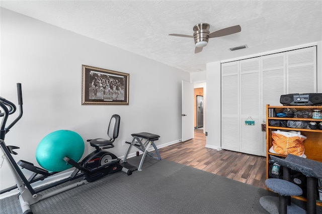 workout room featuring ceiling fan, dark hardwood / wood-style flooring, and a textured ceiling