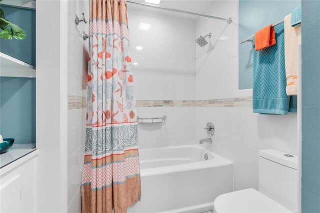 bathroom with tile walls, toilet, and shower / bath combo