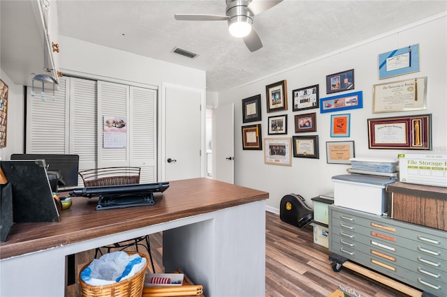 home office with a textured ceiling, dark wood-type flooring, and ceiling fan