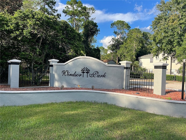 community / neighborhood sign featuring a lawn and fence