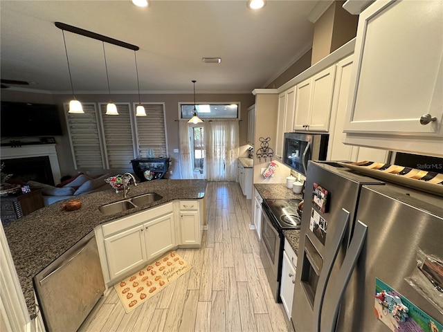 kitchen with appliances with stainless steel finishes, sink, hanging light fixtures, light hardwood / wood-style floors, and white cabinets